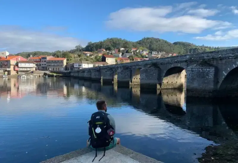 Un peregrino sentado junto a un puente