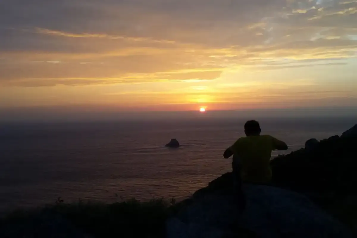 Pilgrim contemplating sunset at Cape Finisterre